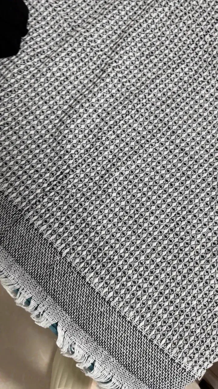 Sofa towel blanket in cream and black wind-cotton yarn with fringed edges by Simples Market