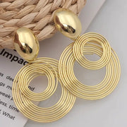 Gold-tone large circular statement earrings with stacked concentric hoops, dangle drop style