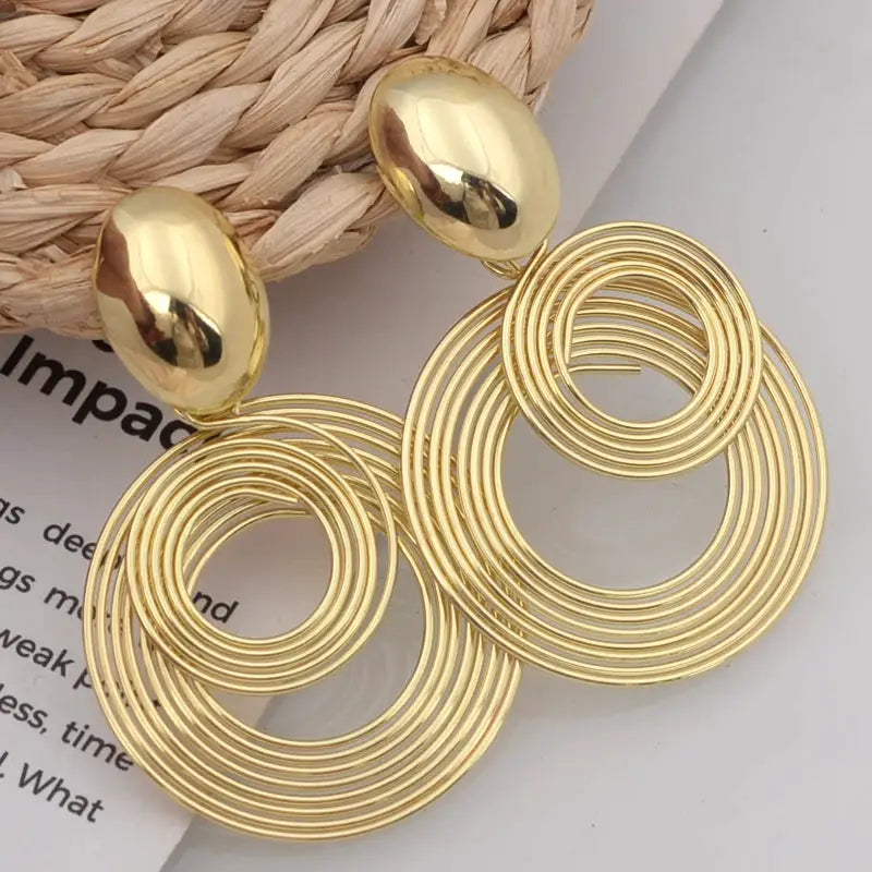 Gold-tone large circular statement earrings with stacked concentric hoops, dangle drop style