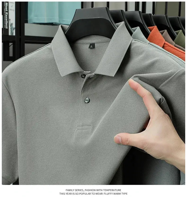 Men's light gray polo shirt, 100% cotton, breathable with silk-like finish; several color options visible on rack.