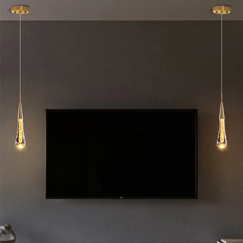 Crystal LED pendant lights with gold finish, two teardrop crystal lamps hanging beside a wall TV.