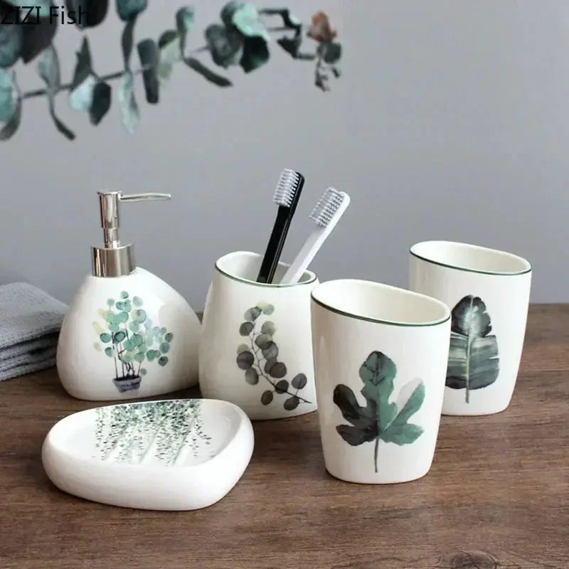 White ceramic bathroom set with botanical prints: soap dispenser, toothbrush holders, mouthwash cup, soap dish.