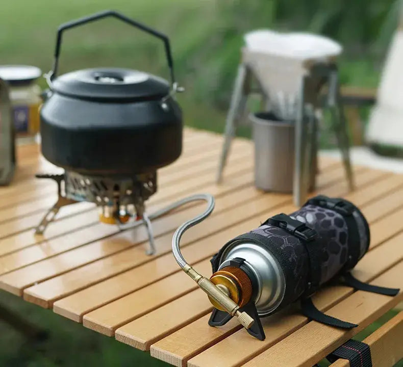 Two camping stoves with Simples Market butane adapter bracket; black patterned canister, brass valve, silver hose