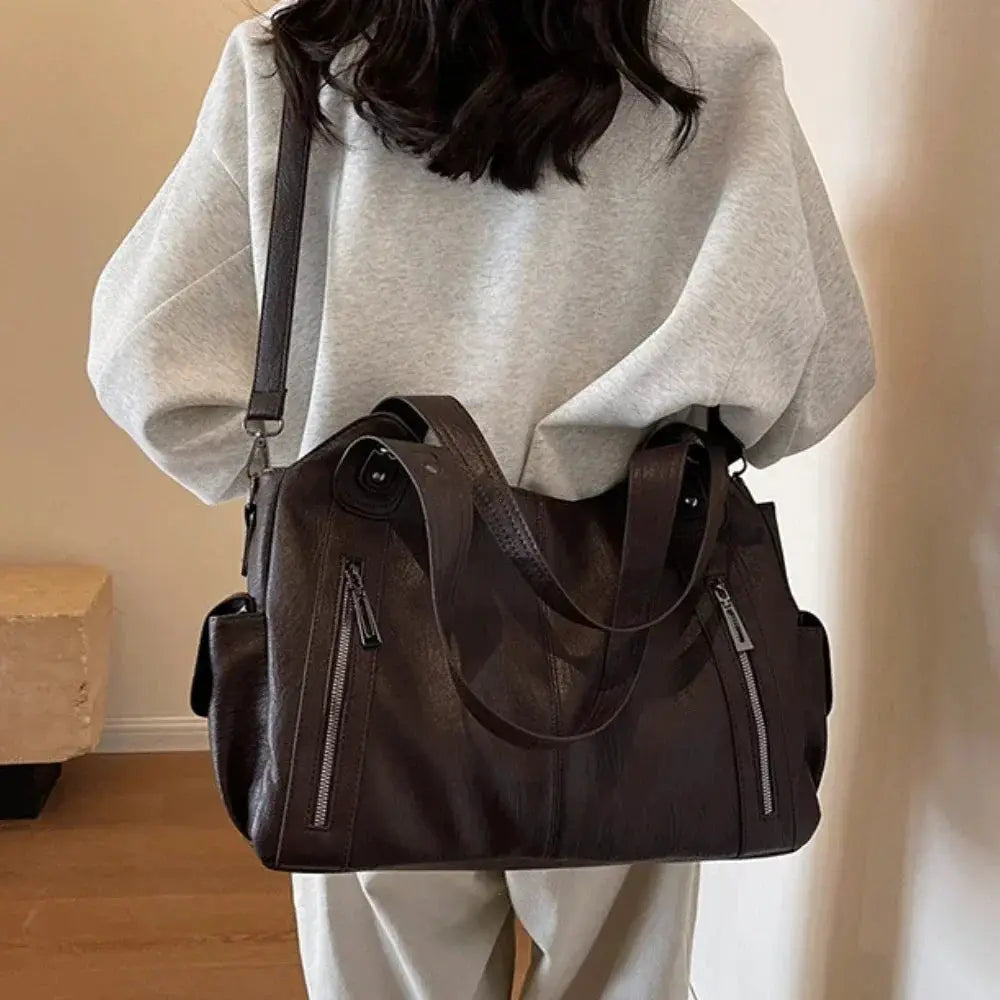 Soft interior compartment shoulder bag in dark brown PU leather with dual zippers and top handles by Simples Market