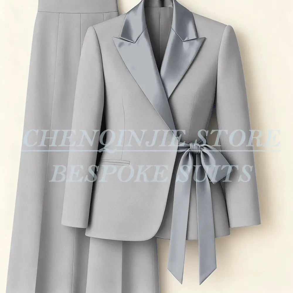 Two-piece women's light gray suit blazer with satin peak lapels and waist-tie belt, paired with matching pants.