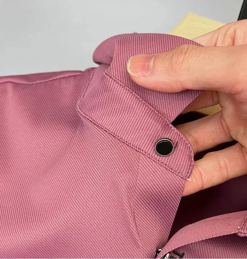 Pink ice silk polo shirt with collar tab and black snap button, close-up of fine ribbed fabric.
