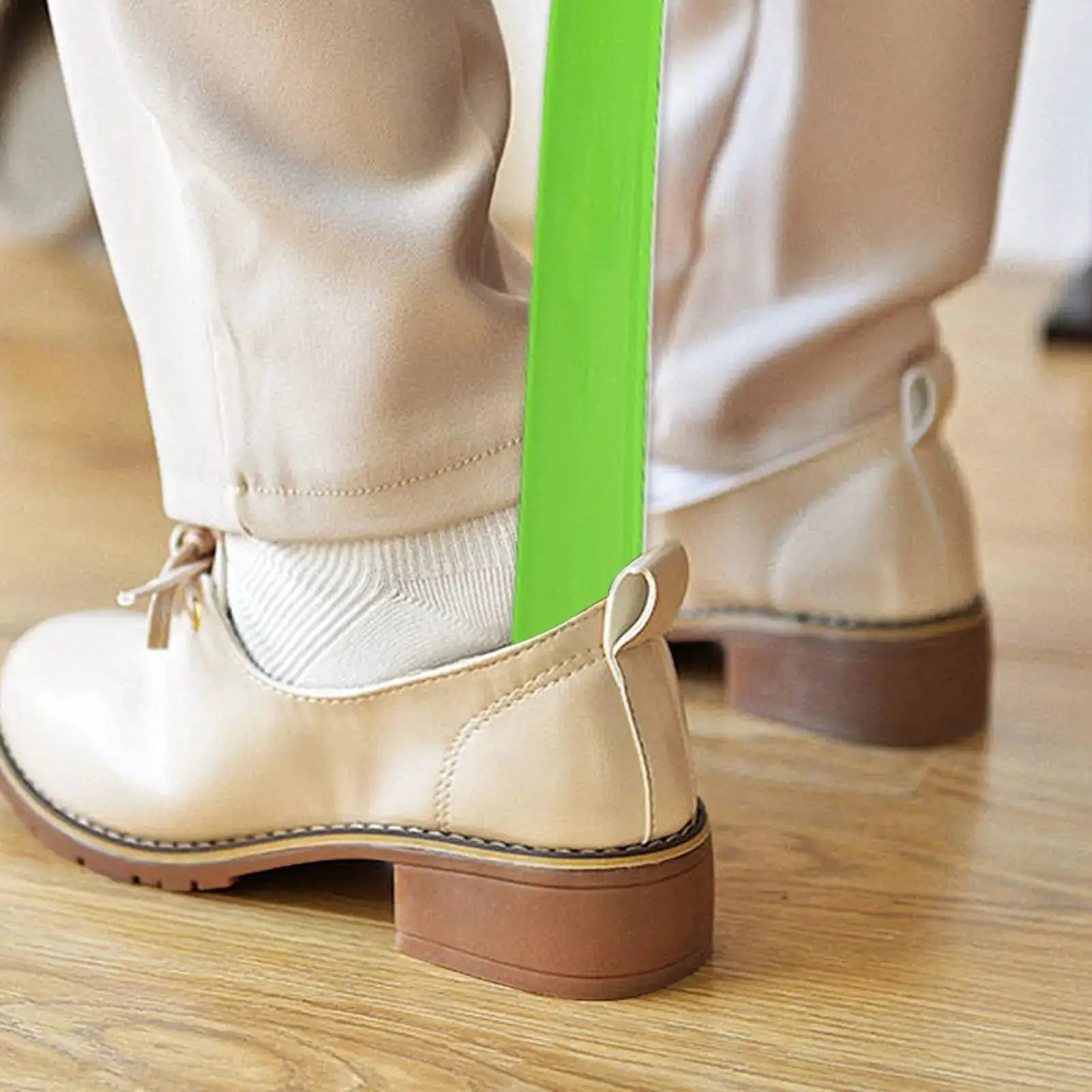Plastic extra-long shoehorn in neon green between beige ankle boots.