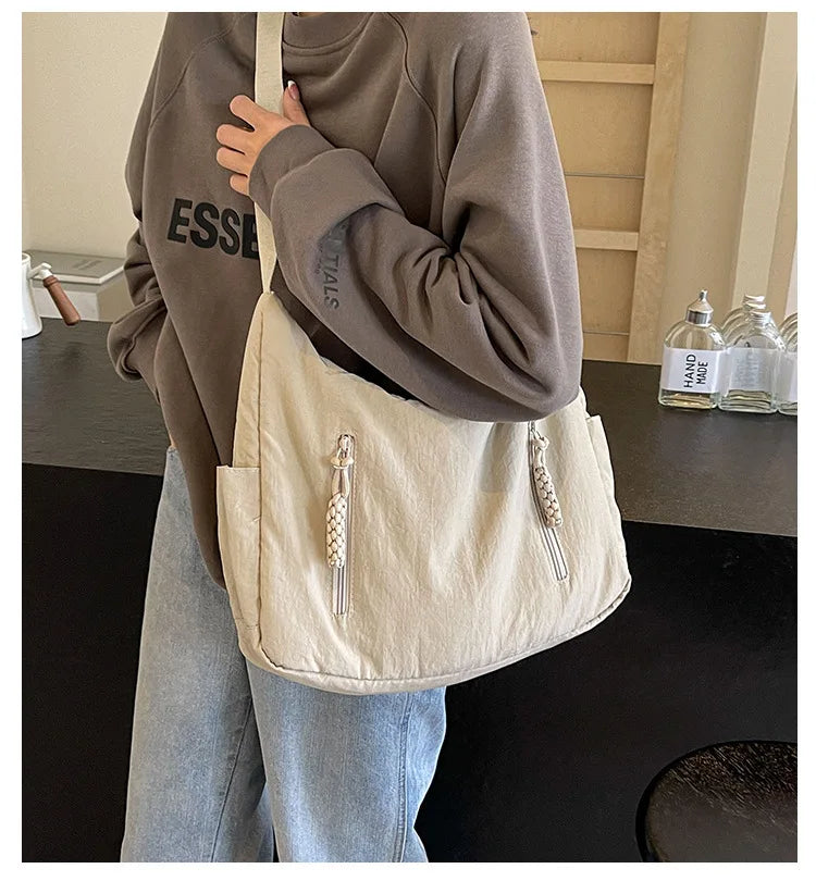 Shoulder bag in cream with two front zip pockets and tassel pulls, crossbody bag