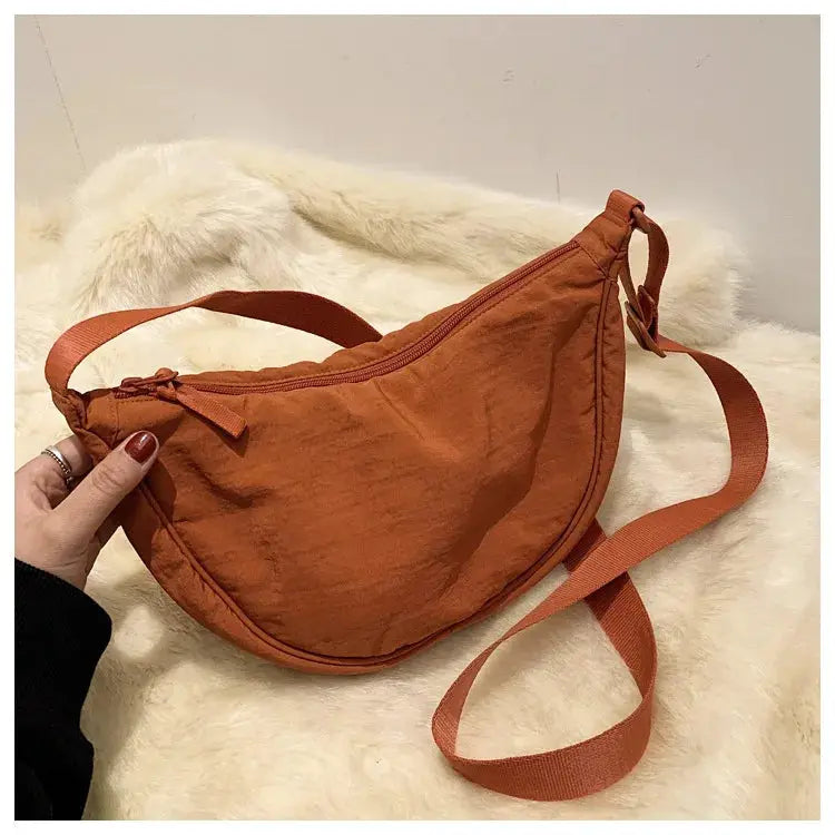 Casual nylon hobo crossbody bag in rust orange with adjustable strap and zip closure.