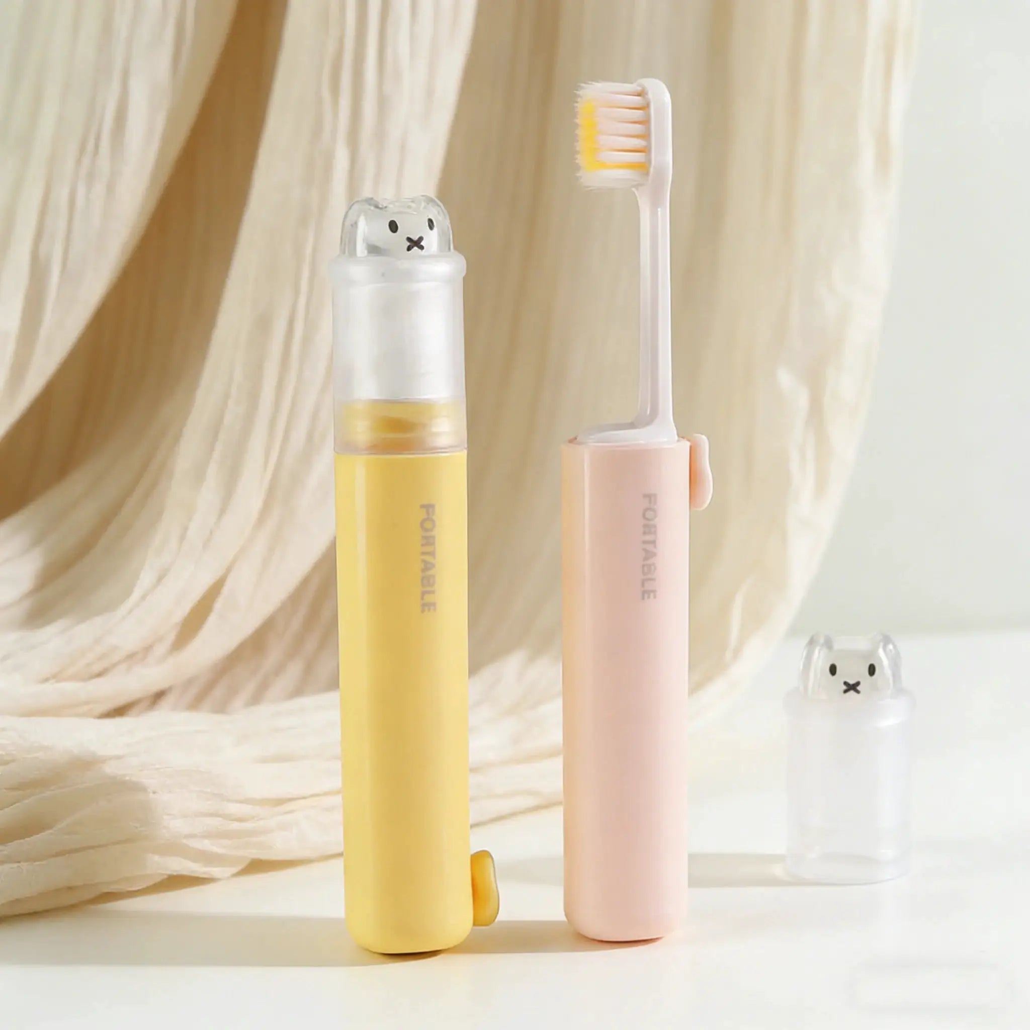 2-in-1 foldable travel toothbrush set with bear-shaped caps in yellow and pink.