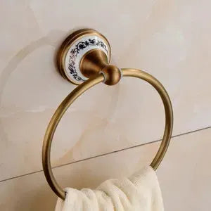 Brushed solid brass towel ring with porcelain blue-floral backplate on tiled wall.
