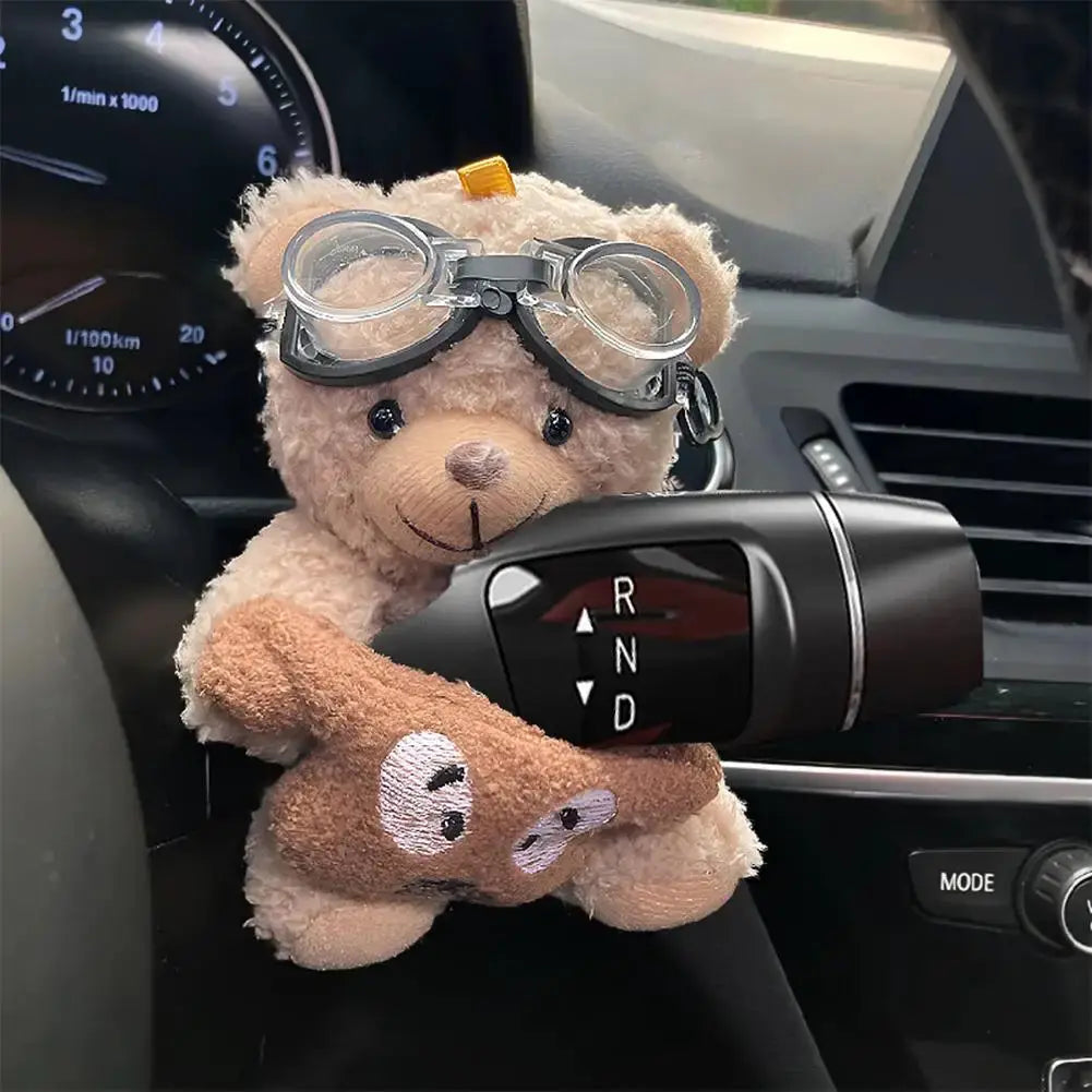 Pilot Bear car ornament by Simples Market; beige plush teddy wearing goggles perched on the gear shift