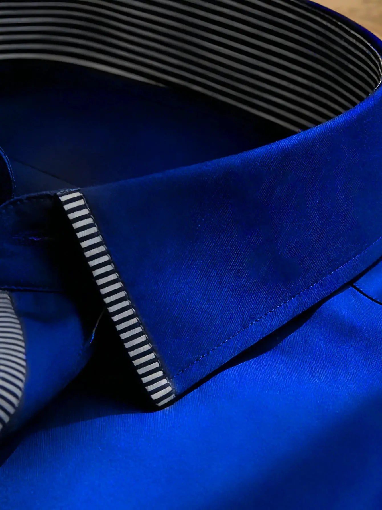 Blue satin shirt cuff with black-and-white striped lining, close-up detail