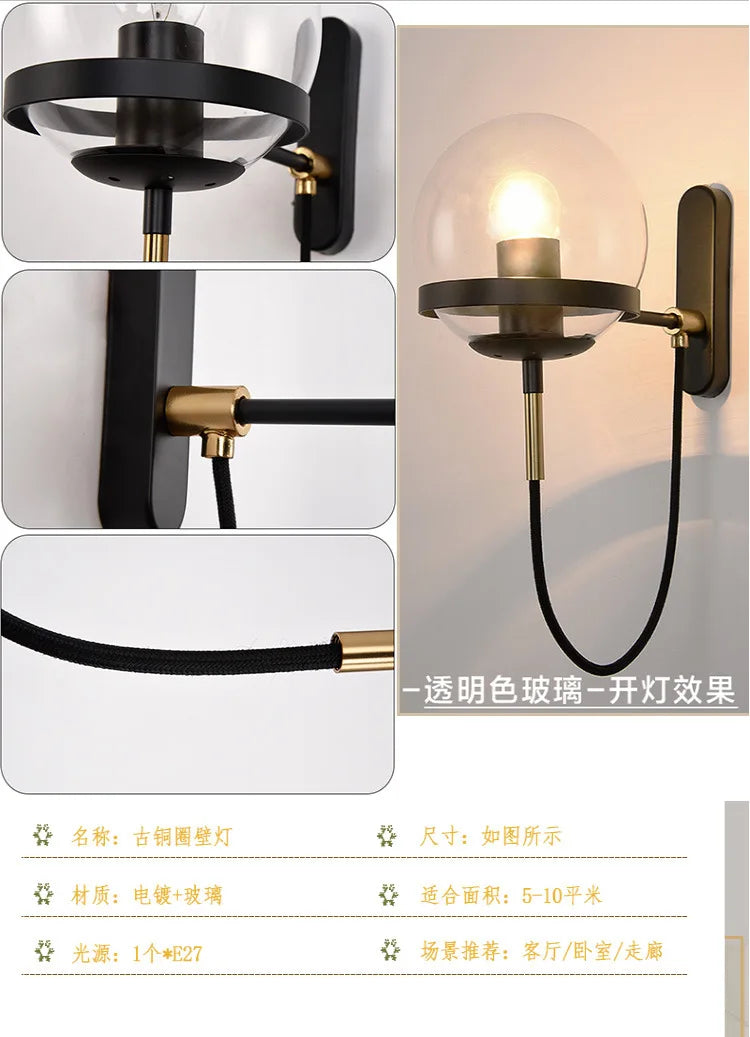 Modern glass ball wall lamp in black metal with brass accents and transparent globe, E27 socket, fabric cord.