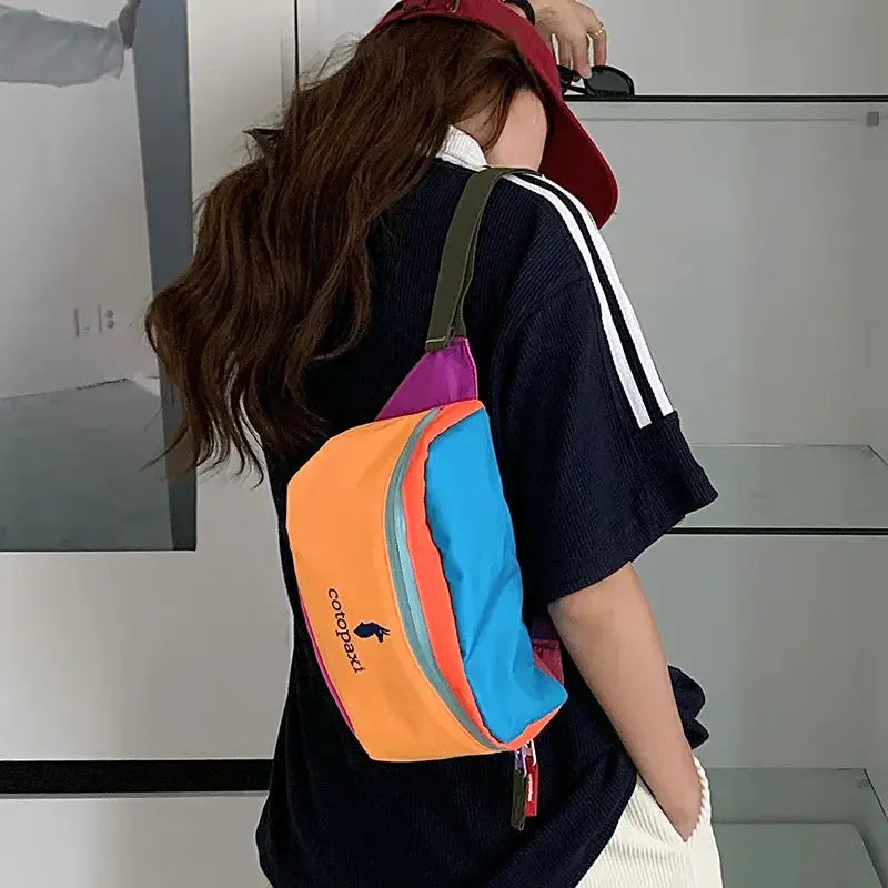 Cotopaxi crossbody bag; multicolor orange front, blue side panels, pink trim, olive-green strap