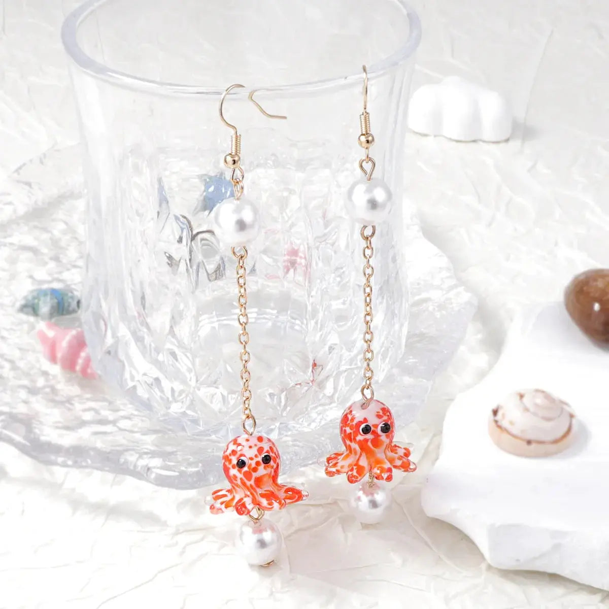 Cute octopus earrings pair by Simples Market with orange-red octopus charms, white pearls, and gold chains