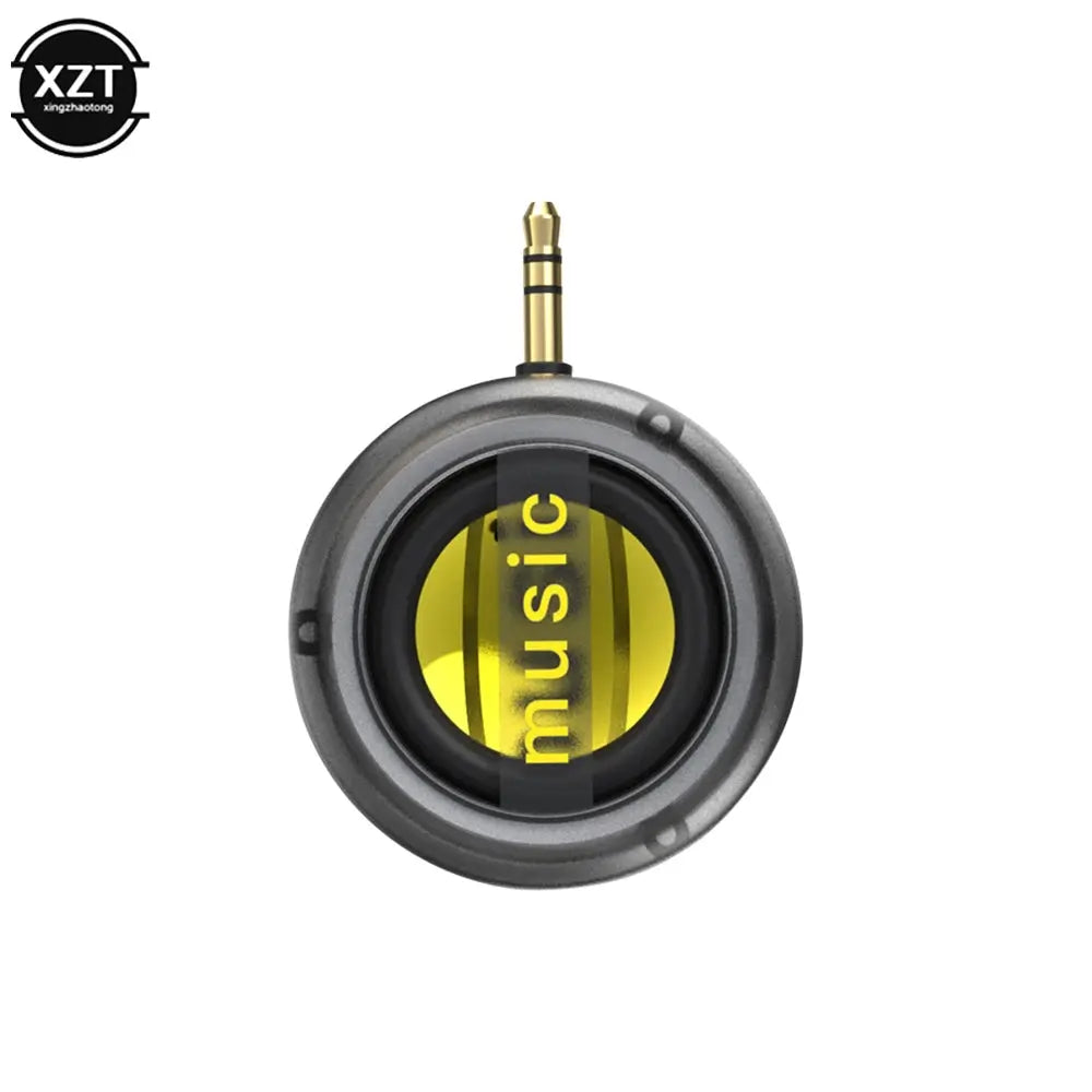 Portable round music speaker with gold 3.5mm plug; gray body with yellow accent