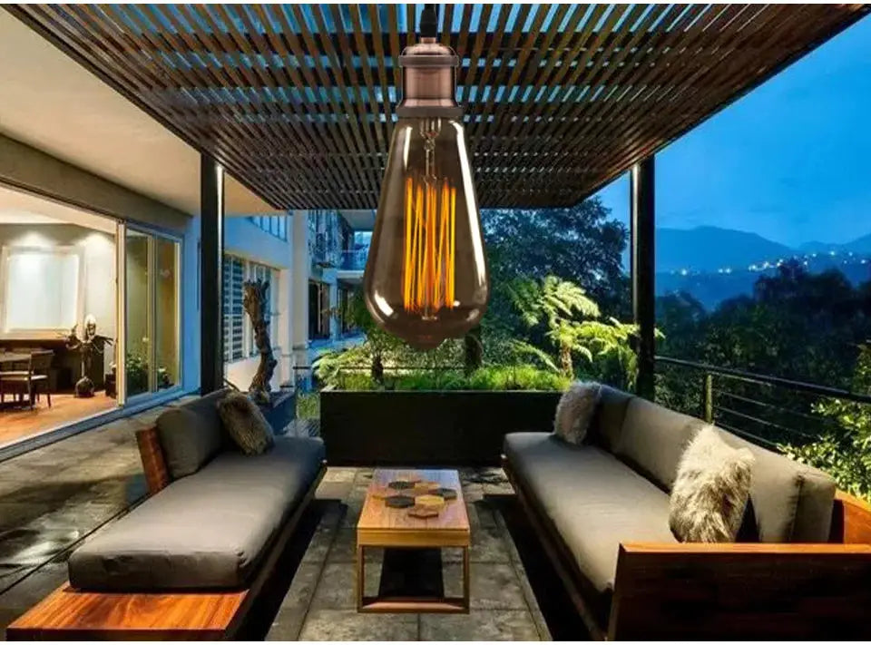 Aluminum pendant light, copper-toned industrial hanging lamp with Edison bulb over outdoor patio lounge.