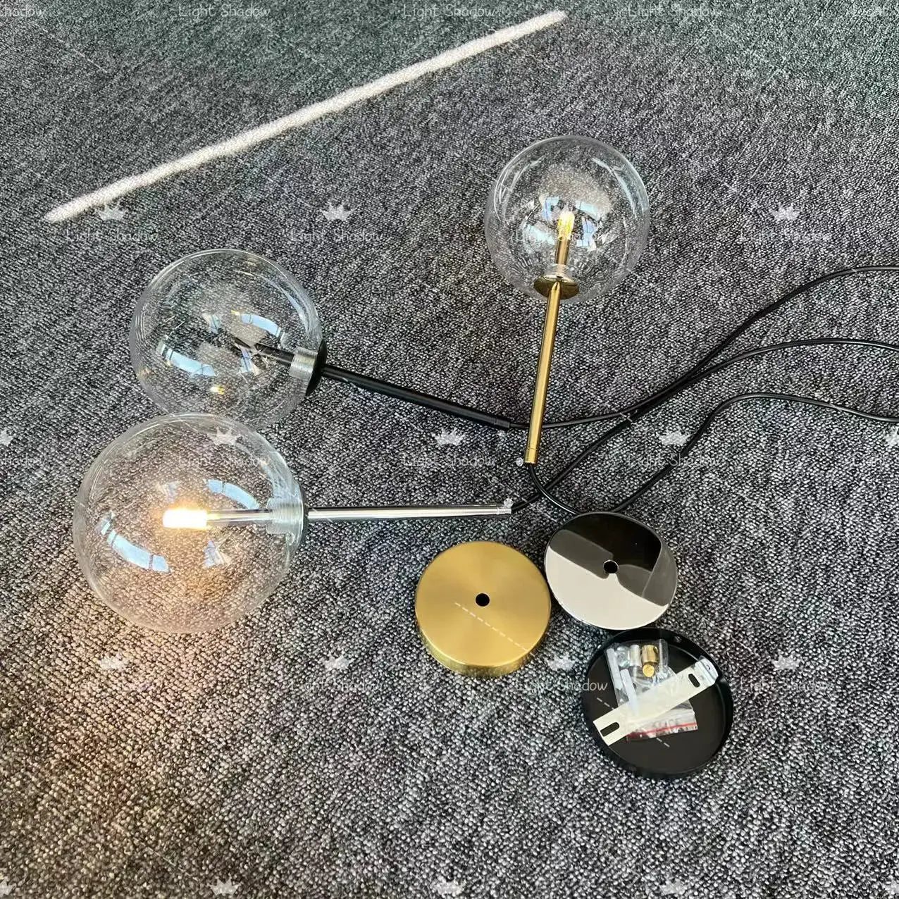 Modern LED pendant lamp with three glass globe bulbs on mixed metal stems (gold, black) and ceiling mounts.