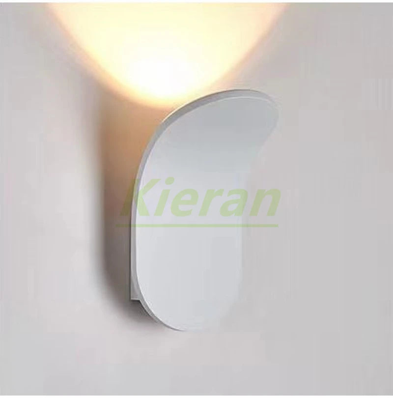 White curved Nordic LED wall lamp, wall-mounted fixture emitting warm ambient light for bedroom or living room decor.