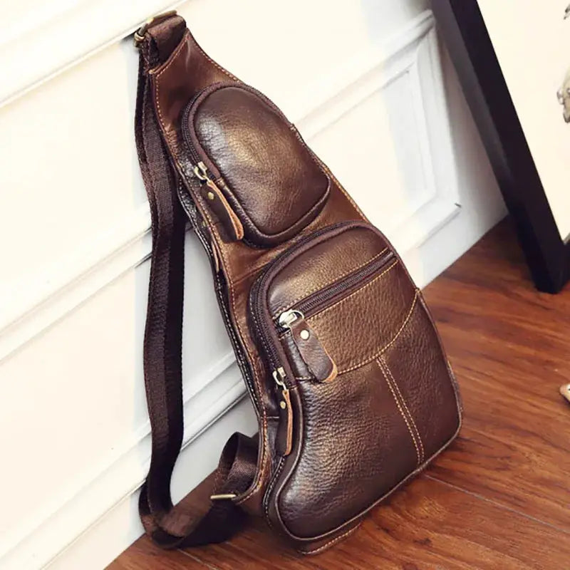 Men's brown genuine leather crossbody sling backpack with two zip pockets and adjustable strap.