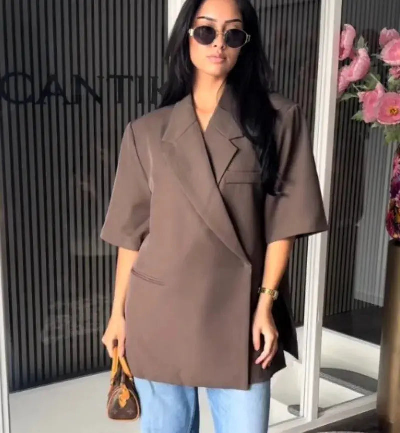 Brown oversized ladies blazer with turn-down collar and single-button closure, worn over jeans