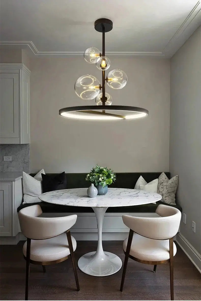 Modern Art Glass Chandelier with clear glass globes on a bronze stem above a round marble dining table.