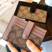 Simples Market card holder wallets (2): pink pebbled wallet with snap strap and brown monogram envelope wallet.