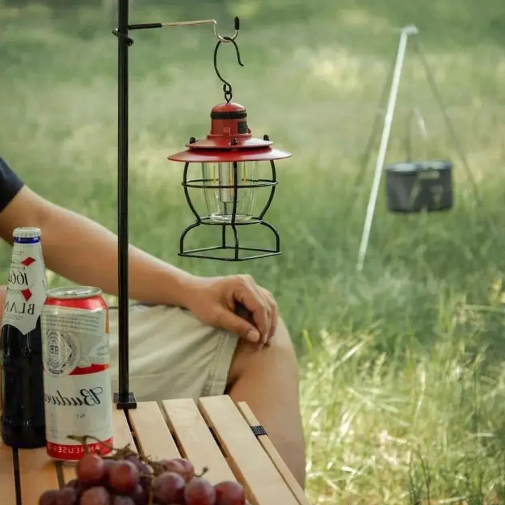 Lantern hanger: red camping lantern suspended from a metal hook on a portable light stand