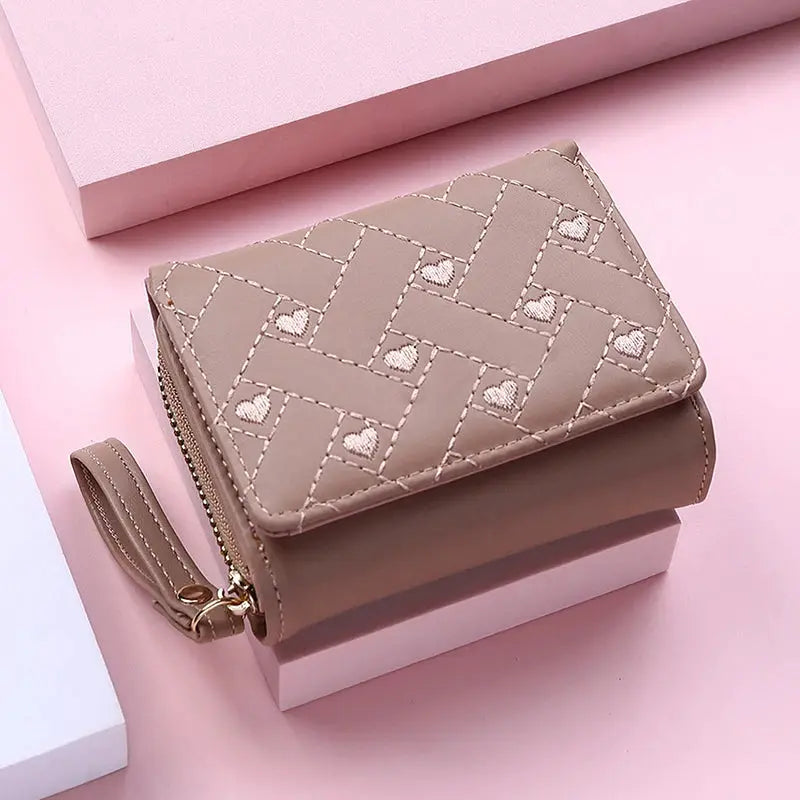 Women's beige PU leather tri-fold wallet with quilted pattern and heart embroidery, wrist strap.