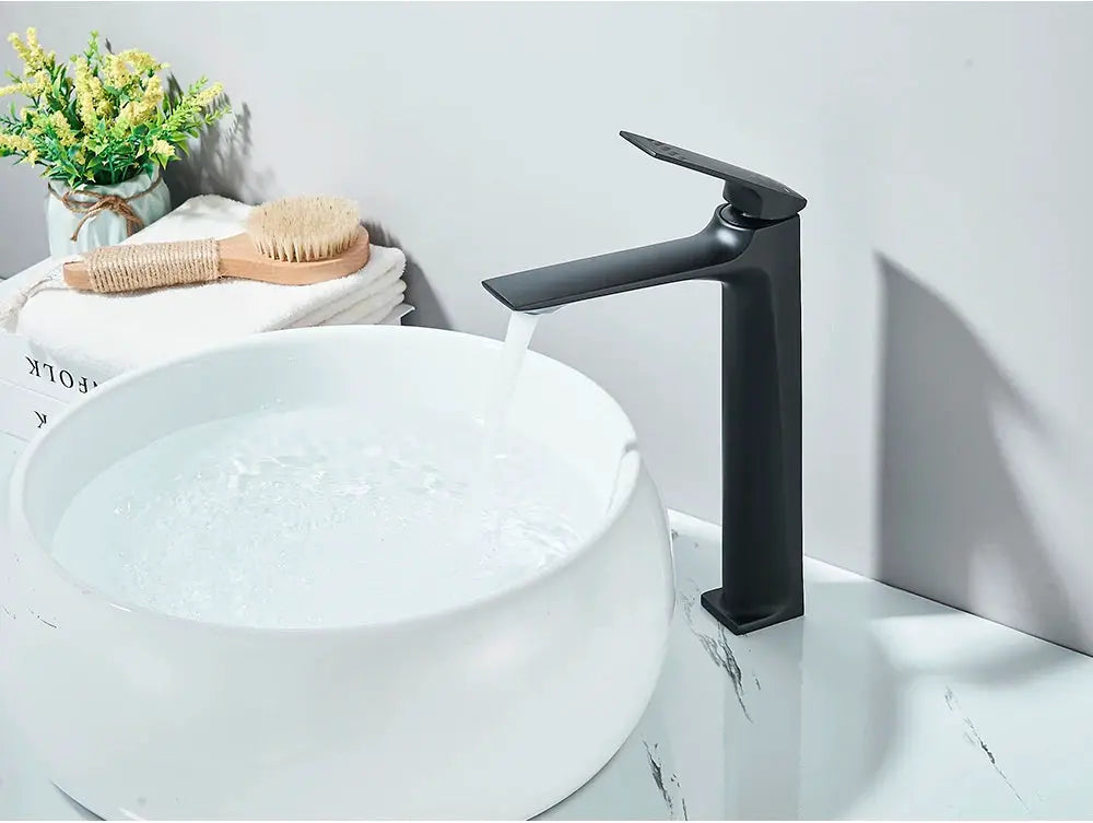 Black matte deck-mounted bathroom faucet with a single lever over a white round basin sink