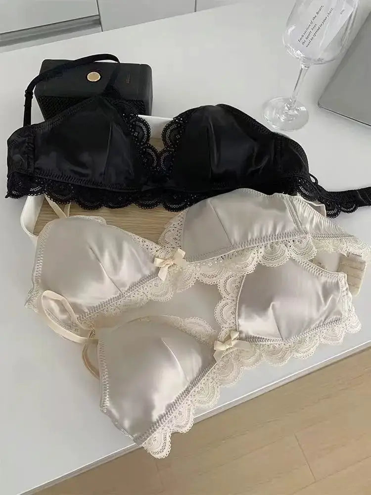 Three SP&CITY triangle-cup lace bras set in black and cream satin with bows, by Simples Market
