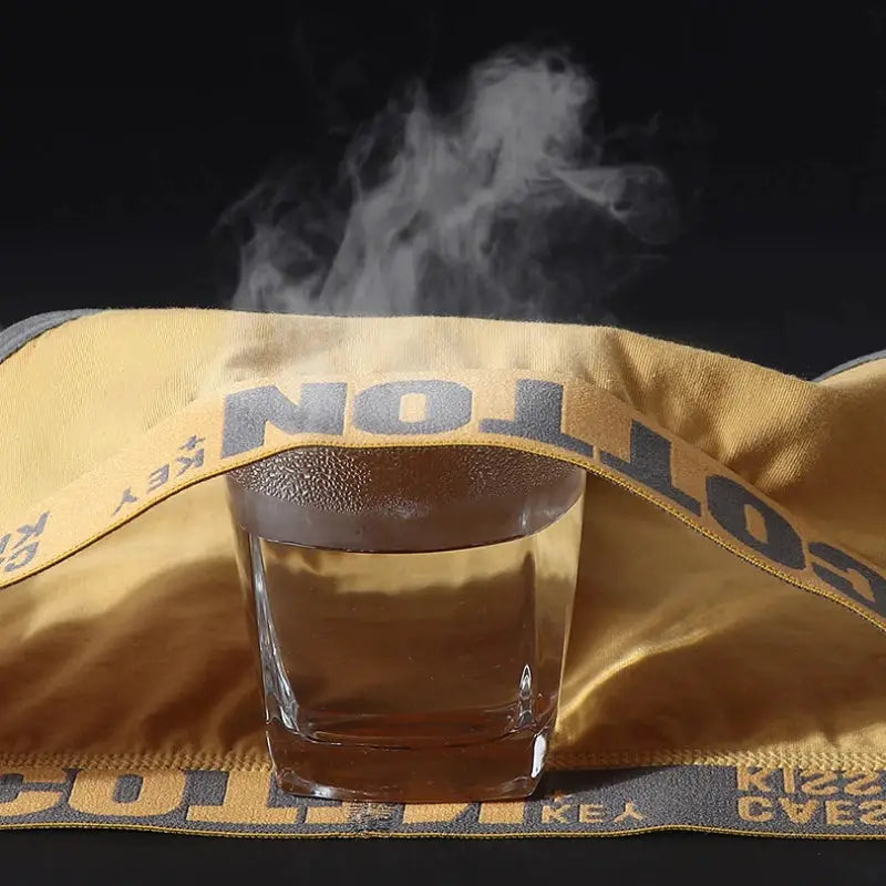 Drinking glass with steam wrapped by beige caution tape over yellow fabric