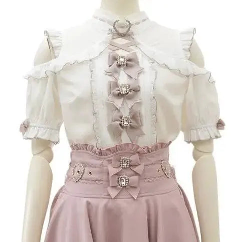 Girls' white Lolita blouse with lace trim, frills, and pink bow accents paired with a pink waist belt