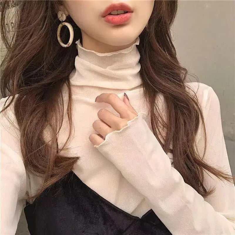 Women's cream high-neck long-sleeve top with frayed cuffs, paired with a black overlay