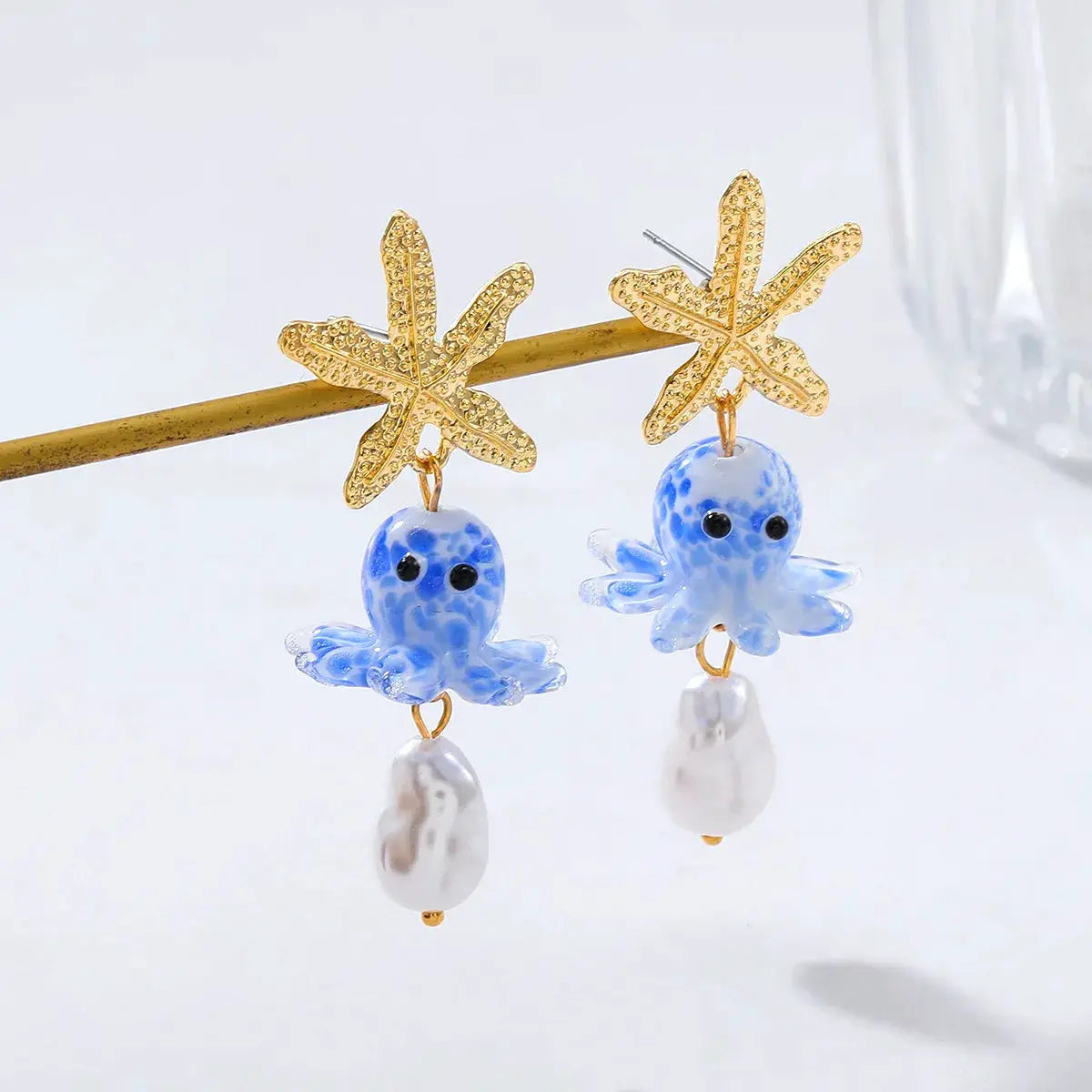 Cute octopus earrings pair with gold starfish tops, blue glass octopus charms and pearl drops.