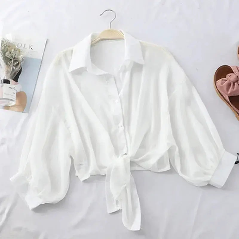 White chiffon blouse with tied waist, bat sleeves, and button front for a casual summer look.
