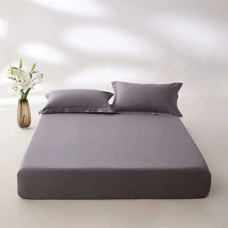 Egyptian cotton fitted sheet in grey on bed with two matching grey pillowcases