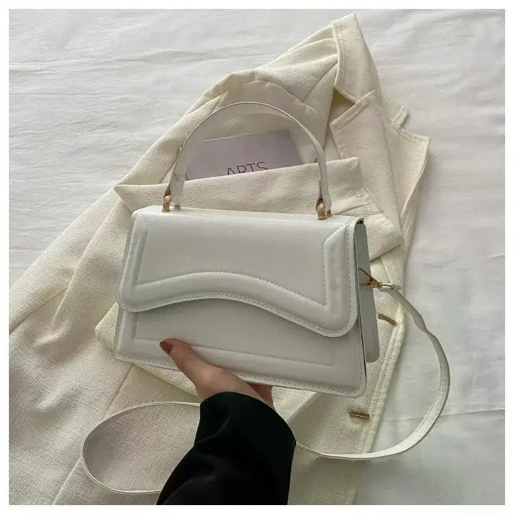 White PU leather handbag with curved flap, top handle and detachable crossbody strap