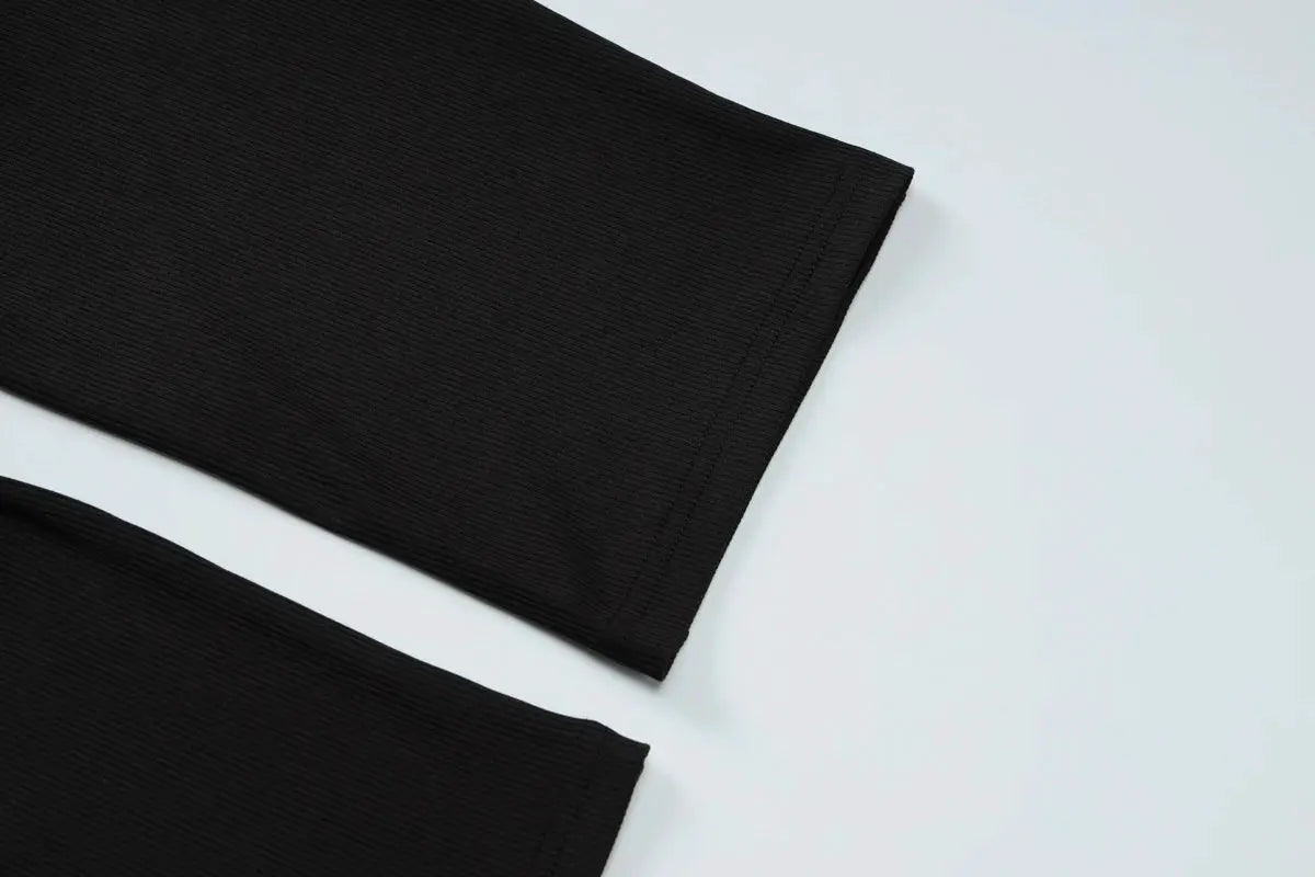 Jumpsuit fabric close-up in black ribbed knit with visible seam hems