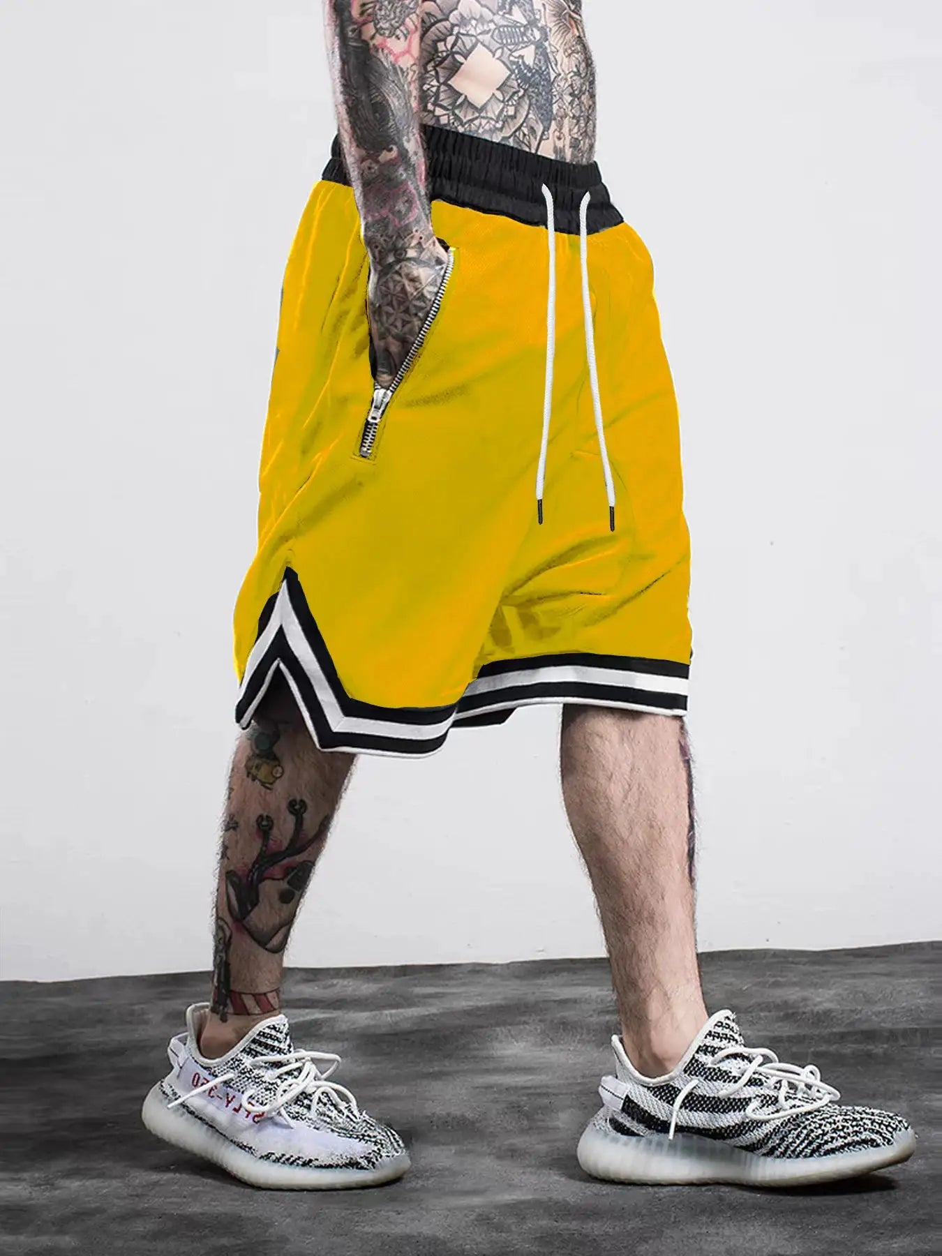 Men's yellow gym shorts with black waist, white drawstrings, and zip side pocket; black-white striped hem.
