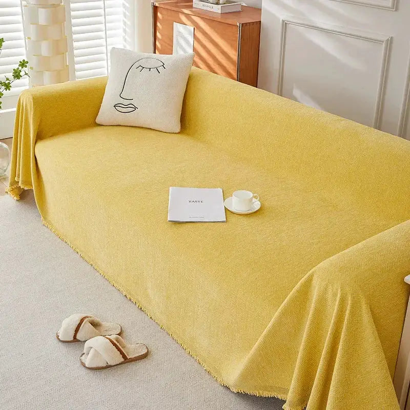 Luxurious chenille couch cover in warm yellow with fringe on a sofa, paired with a decorative cushion.