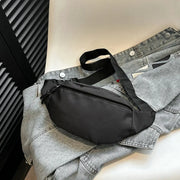 Fanny pack waist bag by Simples Market in black with adjustable strap, placed on a gray denim jacket.