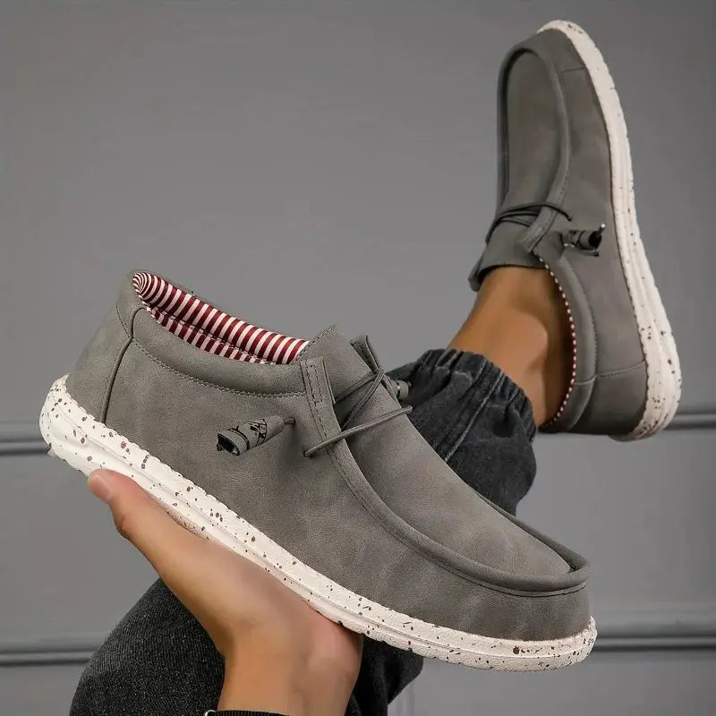 Pair of men's grey suede slip-on loafers with a speckled white sole and striped lining