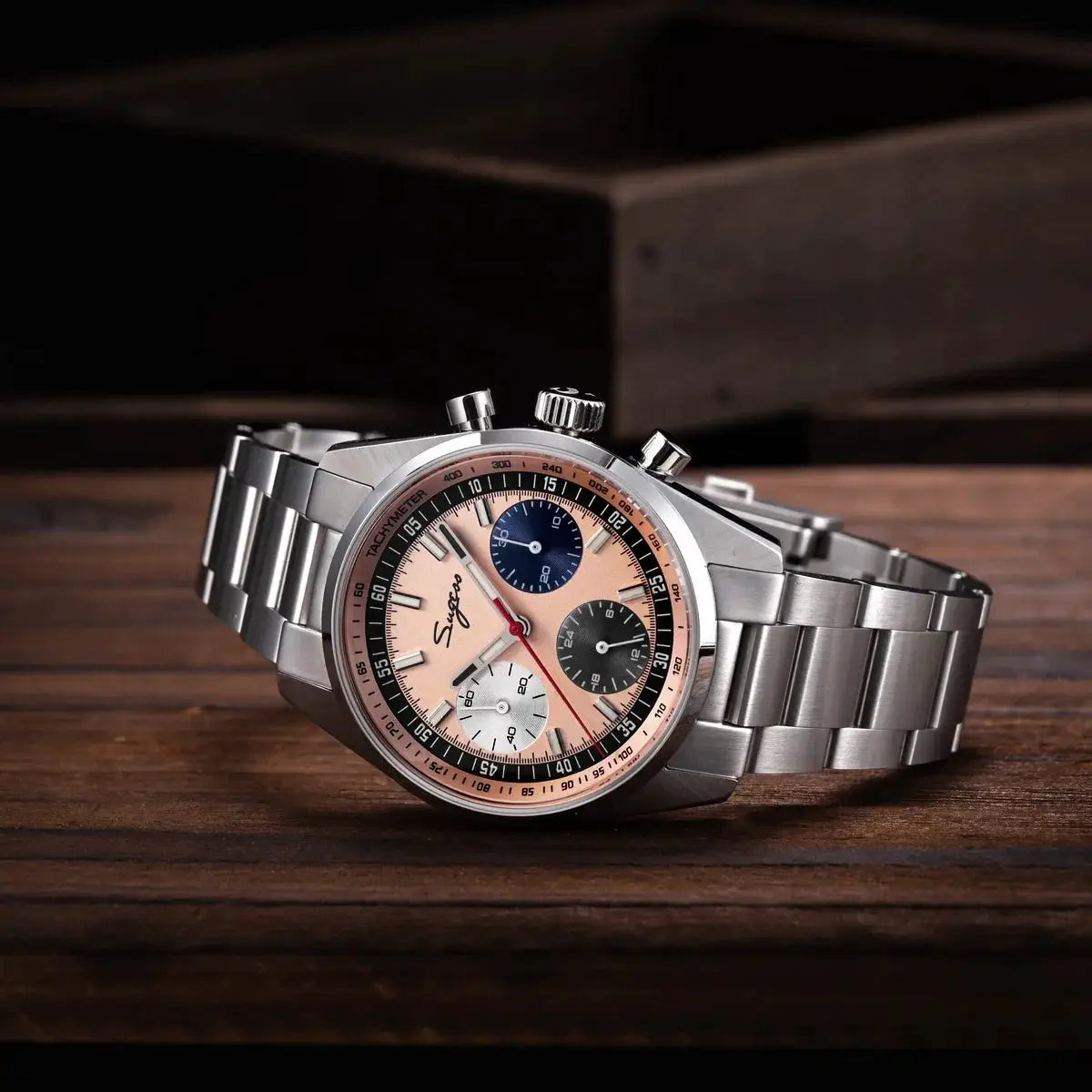 Sugess men's 38mm chronograph watch on stainless steel bracelet with peach dial, tachymeter bezel, and three subdials.