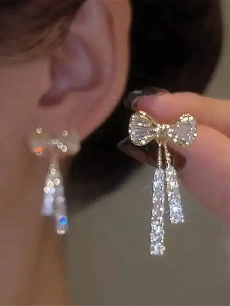Pair of gold-tone bow crystal zircon earrings with dangling crystal tassels by Simples Market