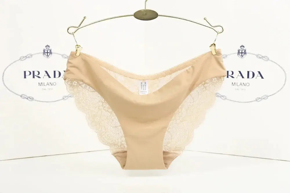 Simples Market beige seamless lace panties with wide lace side panels, hanging against a Prada backdrop.