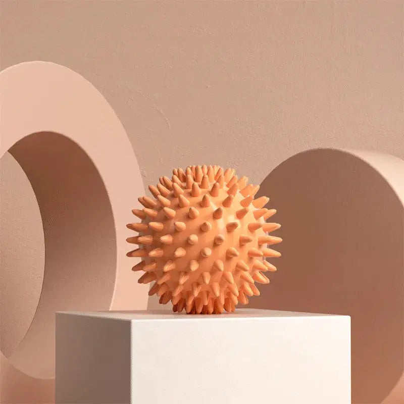 Simples Market peach-colored spiky fascia massage ball on a white pedestal for muscle relaxation and yoga