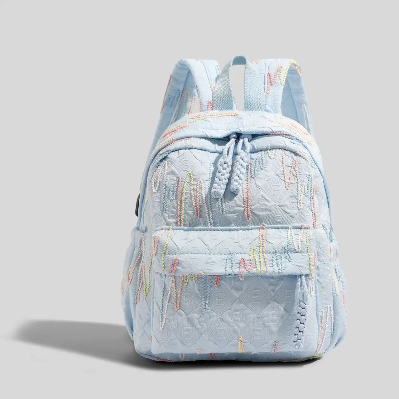 Mini backpack by Simples Market in light blue quilted fabric with pastel embroidery, front pocket, and adjustable straps
