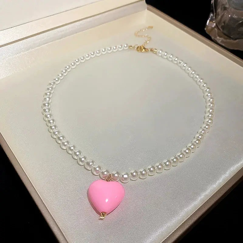 Pearl necklace with pink heart pendant on white choker-style strand by Simples Market, wedding jewelry.